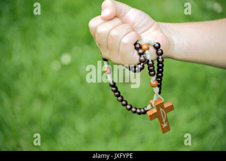 Rosenkranz aus Holz in Kinderhand Stockfoto