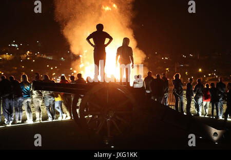 Die Menschen sehen ein Lagerfeuer, von der Spitze einer Kanone auf Derry City Wände in der Bogside Bereich von Londonderry, die traditionell am 15. August torched ist ein katholischer Feiertag feiern die Himmelfahrt der Jungfrau Maria in den Himmel zu markieren, aber in der heutigen Zeit hat das Feuer ein Streitpunkt werden und mit anti-soziales Verhalten verbunden sind. Stockfoto