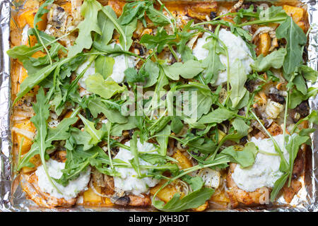 Ofen gebratenes Huhn und Yukon Gold Kartoffeln, Lauch, Rucola und Tzatziki Soße auf ein Backblech mit Alufolie ausgekleidet Stockfoto