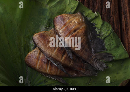 Thai Food getrocknet gesalzen Dirne Fisch gebraten mit Lotus Dekoration lassen auf hölzernen Hintergrund schön flach Stillleben rustikales Asien Stockfoto