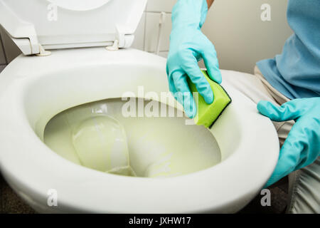 Nahaufnahme der Person Hand Reinigung Wc zu Hause mit Schwamm Stockfoto