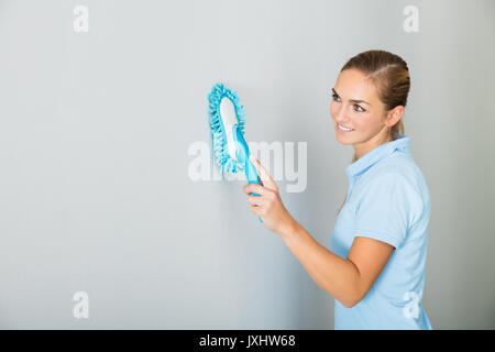 Junge Frau Reinigung der Decke mit Mop auf dem Flur des Gebäudes Stockfoto