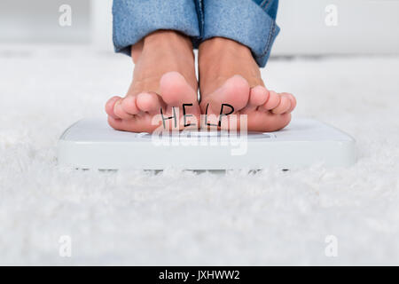 In der Nähe der Person, Stehend auf der Waage Zeigt Hilfetext zu Hause Stockfoto