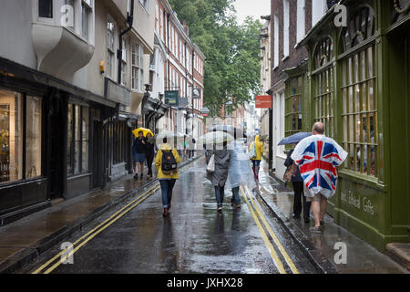 Sehr regnerischen Tag im Zentrum von York, Sonnenschirme und einen Mann, der in einer Union Flag anorak Poncho Stockfoto