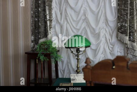 Fragment des Innern Kabinett, Tisch am Fenster mit Vorhängen und bronze Lampe mit grünen Schatten Stockfoto