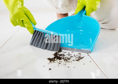 Nahaufnahme der Person mit Handschuhen fegen Stock mit Besen und Kehrblech Stockfoto