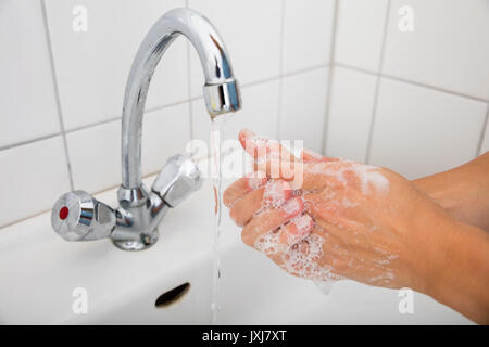 In der Nähe von Frau Seife anwenden, während die Hände waschen in Becken mit Öffnen. Stockfoto