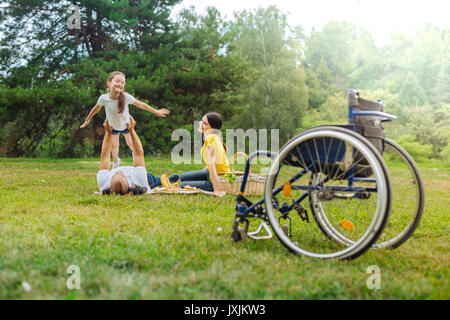 Fröhliches Mädchen spielen mit ihren behinderten Vater liegen auf Gras Stockfoto