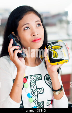 Junge asiatische Frau mit retro Nokia Telefon und WALKMAN® Sport Stockfoto