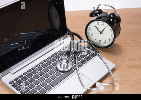 Über dem Kopf von Schwarz und Silber medizinische Stethoskop liegen auf Laptop Tastatur neben Wecker Stockfoto