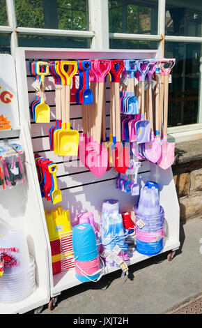 Plastikeimer und Spade Spielzeug zum Verkauf außerhalb des Ladengeschäfts neben dem Strand im Sommer Scarborough North Yorkshire England Großbritannien Stockfoto