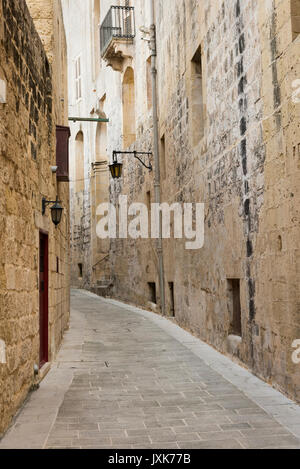 Eine schmale Straße, das in der ummauerten Stadt Mdina Malta gesäumt von alten Steinmauern - die stille Stadt Stockfoto