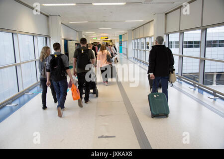 Passagiere mit Gepäck zu Fuß entlang der Flur im Nordterminal des Flughafen Gatwick, London, England, Großbritannien Stockfoto