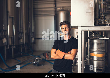 Porträt der jungen Mann mit Bier befüllen. Brauerei Arbeiter mit industriellen Geräten. Stockfoto