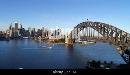 Antenne weiten Blick über den Hafen von Sydney über Bogen der Harbour Bridge in Richtung the Rocks, Circular Quay und CBD hoch aufragenden Türmen. Stockfoto