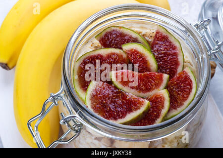 Old Fashion Hafer mit griechischem Joghurt, Banane und Feigen in einem Glas auf weißen Hintergrund im Landhausstil Stockfoto