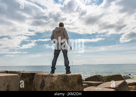 Von hinten ein Mann stand auf Felsen, mit Meerblick. Stockfoto