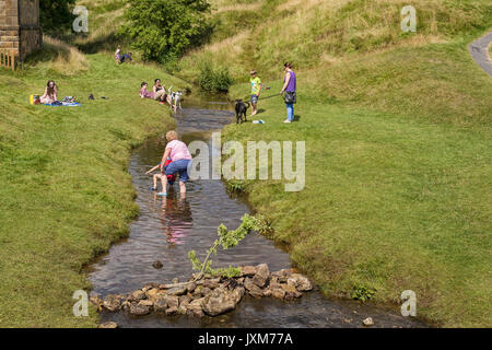 Touristen in einem Stream von Hutton le Hole Village, North York Moors, Yorkshire, England, Großbritannien Stockfoto