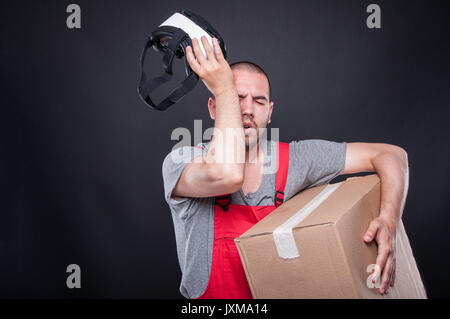 Mover guy Holding Box aus VR-Brille und rieb seine Augen auf schwarzem Hintergrund Stockfoto