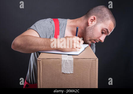 Mover Kerl Notizen von Kartons auf schwarzem Hintergrund Stockfoto