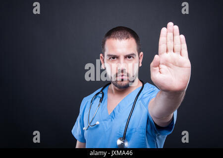 Portrait von männlicher Arzt zeigt stop Geste auf schwarzen Hintergrund mit Kopie Raum Raum für Werbung Stockfoto