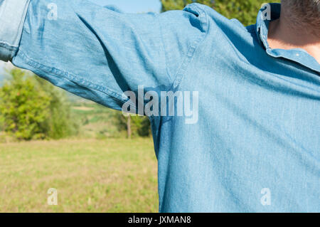 Sommerhitze Konzept mit männlicher underarm in Nahaufnahme mit Makel der Schweiß auf Shirt Stockfoto