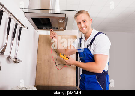 Junge männliche Techniker prüfen Abzugshaube Filter mit digitaler Multimeter Stockfoto