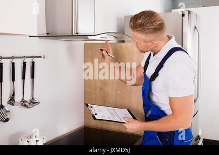 Junge männliche Handwerker mit Zwischenablage Abzugshaube Filter prüfen. Stockfoto