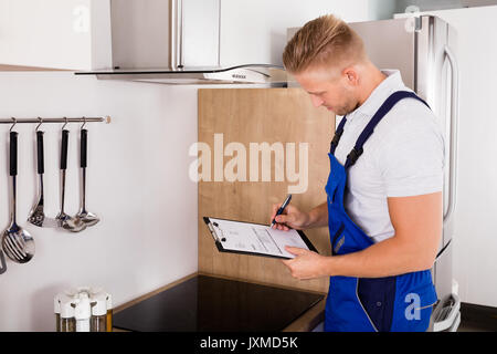 Junge männliche Handwerker mit Zwischenablage Abzugshaube Filter prüfen. Stockfoto