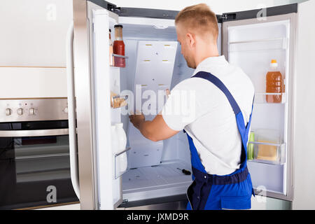 Junge männliche Handwerker zur Festsetzung der Kühlschrank in der Küche Stockfoto