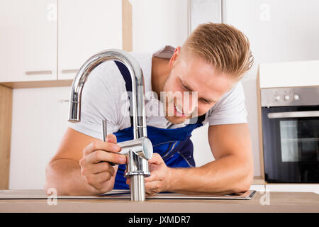Glückliche junge männliche Klempner zur Festsetzung der Wasserhahn in der Küche Stockfoto