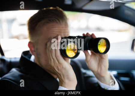 Privatdetektiv Sitzen im Auto durch Fernglas Stockfoto