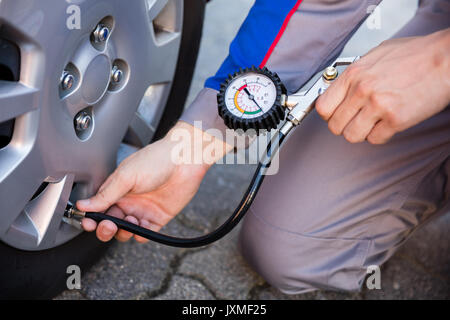 Person Messen auto Reifendruck mit einem Manometer Stockfoto