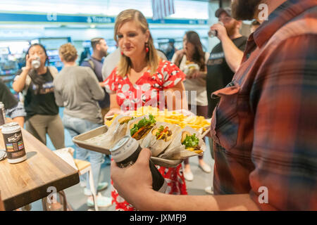 Scharen von Hungernden burger Liebhaber und durstigen Biertrinkern in Scharen in die Shake Shack in der Penn Station in New York am Montag, 14. August 2017 Für die Happy Hour Debüt party von Blue's Point Brauerei Rufumleitung' Bier. Als Reaktion auf die 'Summer der Hölle', die Long Island Railroad Passagiere wegen Wartung track Arbeit Blue Point Brauerei werden erstellt ihre Rufumleitung "Pilsner Bier mit der Grafik auf dem kann ein Riff auf der LIRR Abfahrtstafeln. Die ersten 100 Kunden erhalten einen kostenlosen Burger mit dem Kauf einer Rufumleitung". (© Richard B. Levine) Stockfoto