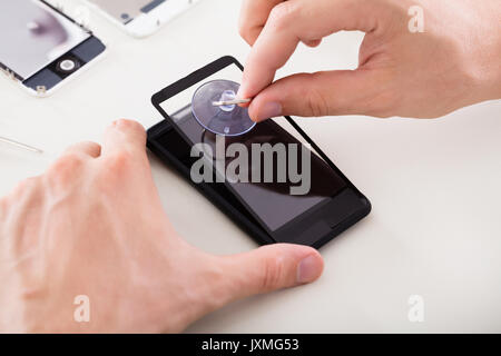 Nahaufnahme von einer Person Hand Instandsetzung der defekten Mobiltelefon Stockfoto