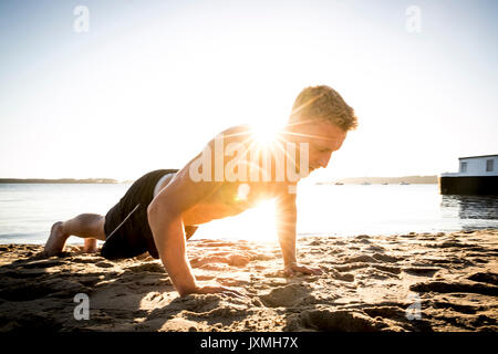 Junger Mann Ausbildung, Push-ups auf sonnigen Strand Stockfoto