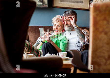 Schrullige vintage Ehepaar am Smartphone im Tee Zimmer suchen Stockfoto