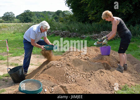 2017 Aylsham Römisch-Projekt - ein Mann und eine Frau Sieb eimer Erde für potenzielle findet Stockfoto