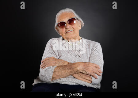 Portrait der älteren Frau mit Sonnenbrille Über grauer Hintergrund Stockfoto