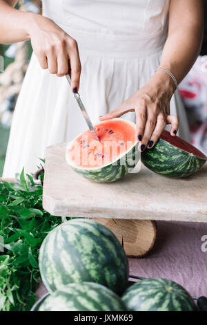 Frau schneid Wassermelone auf Schneidebrett Stockfoto