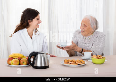 Ältere Frau mit Kaffee zu pflegen, während Sie Kaffee Stockfoto