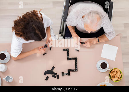 Hohe Betrachtungswinkel der älteren Frau spielen Domino Spiel mit ihrer Amme Stockfoto