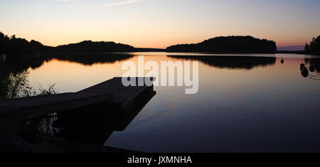Sonnenuntergang auf einer Marina, Reflexion über Wasser, Steg und einige Bojen Stockfoto