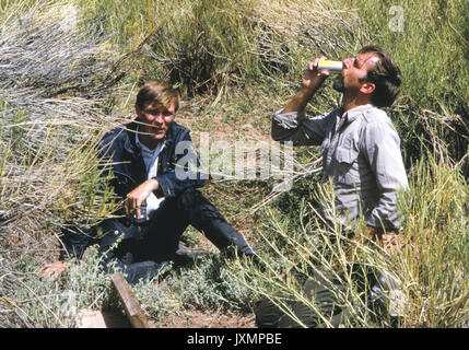 Edward Abbey und Schriftsteller Daniel Chapman trinken kalte Getränke aus einem Kühlschrank in der Wüste im Canyonlands National Park in 1969. Stockfoto