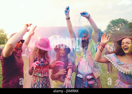 Junge Erwachsene Freunde tanzen und werfen farbige Kreide Pulver bei Festival Stockfoto