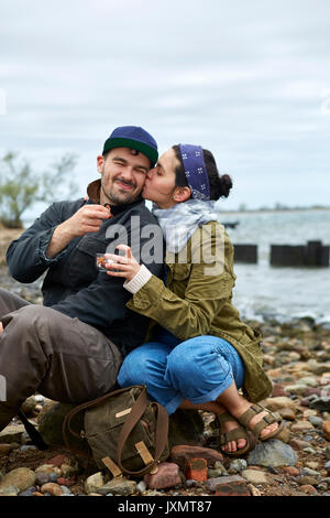 Junge Frau küssen Freund auf Wange am Strand Stockfoto