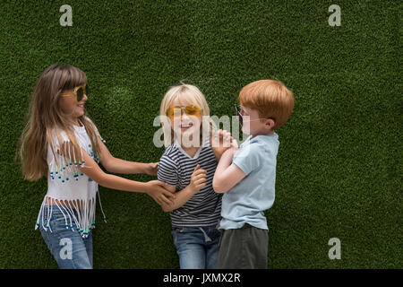 Kinder vor der Kunstrasen Wand spielen Kitzeln Stockfoto