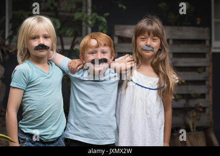 Kinder tragen von gefälschten Schnurrbärten auf Kamera lächeln Stockfoto