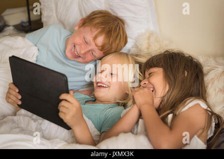 Kinder im Bett lag, auf digitalen Tablet Stockfoto