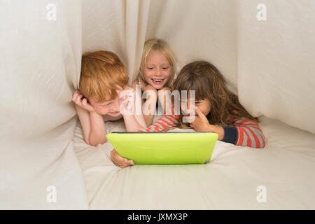 Kinder im Bett lag, auf digitalen Tablet Stockfoto